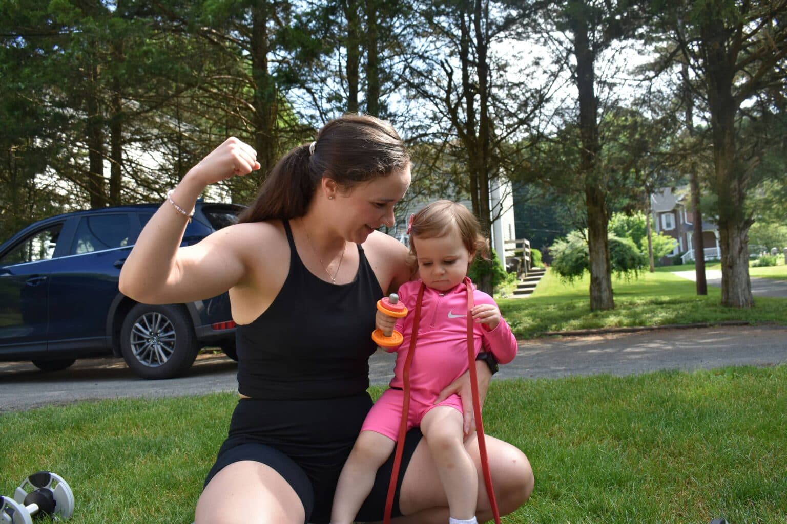 Postpartum mom doing core rehab work on a yoga mat with her toddler nearby