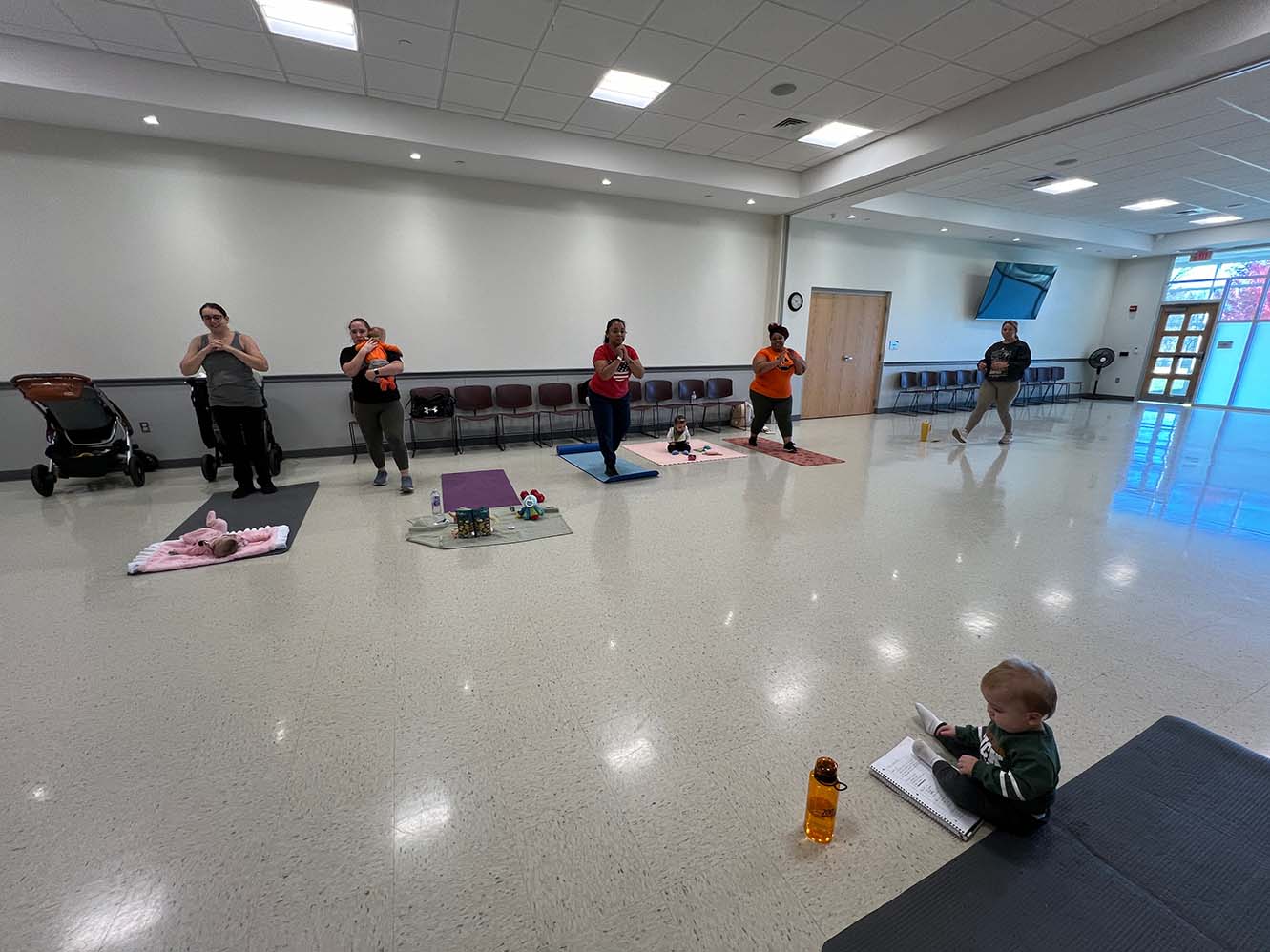 Mom doing squats while holding her baby in a group class